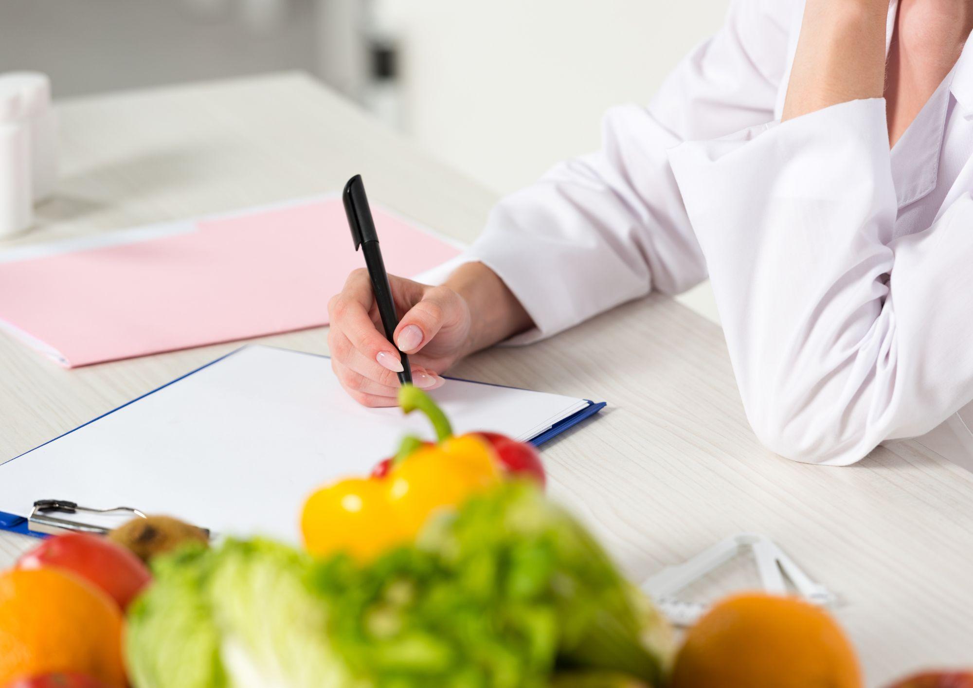 Chica escribiendo en un papel la planificación de comidas que hará durante toda la semana para mantener un estilo equilibrado y saludable