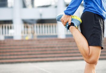 Deportista de elite que se encuentra estirando los músculo antes de salir a hacer running